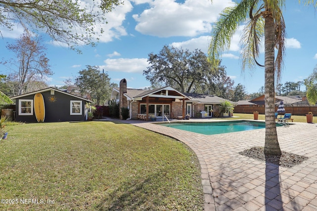 view of pool with a patio area, an outdoor structure, and a lawn