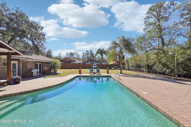 view of pool with grilling area, a yard, and a patio