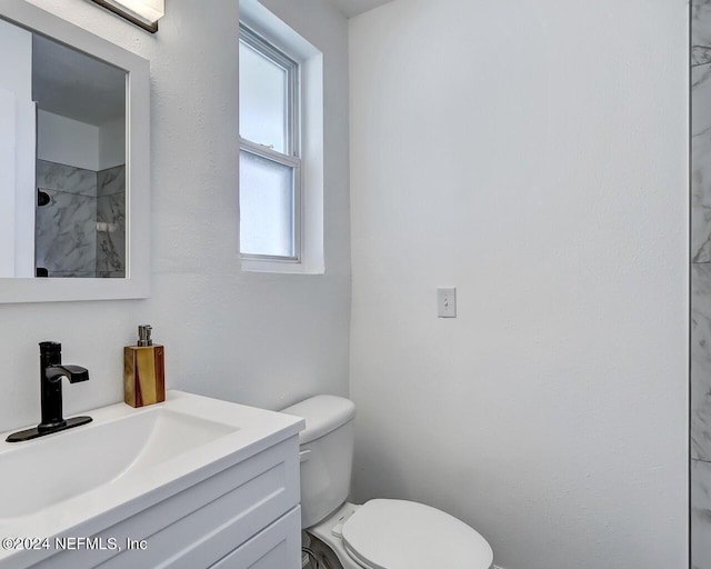 bathroom featuring vanity, walk in shower, and toilet