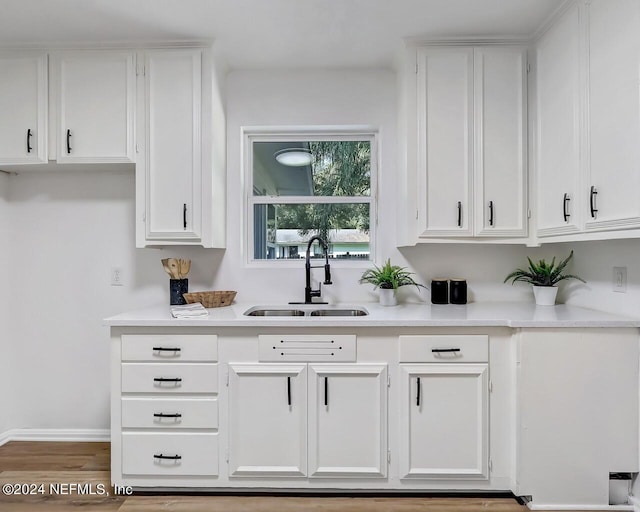 bar featuring sink, white cabinets, and light hardwood / wood-style flooring