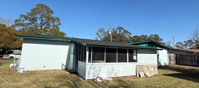 back of property with a lawn and a sunroom