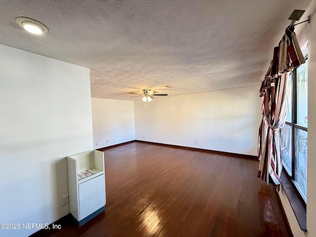 unfurnished room with ceiling fan, dark hardwood / wood-style floors, and a textured ceiling