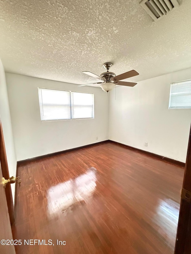 spare room featuring dark wood-type flooring, ceiling fan, and a textured ceiling