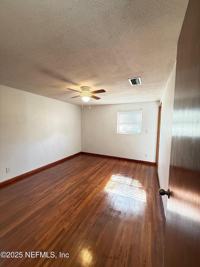 empty room with a textured ceiling, dark hardwood / wood-style floors, and ceiling fan