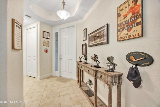 entrance foyer featuring a raised ceiling and light tile patterned floors