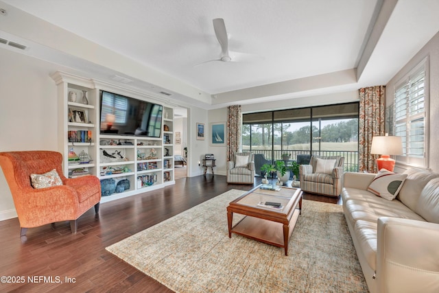 living room with hardwood / wood-style floors, a tray ceiling, and ceiling fan