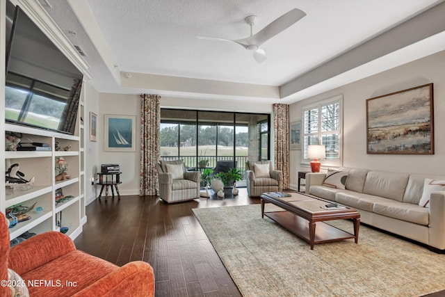 living room featuring ceiling fan, wood-type flooring, a raised ceiling, and a textured ceiling