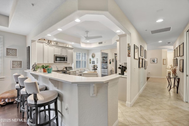 kitchen with stainless steel appliances, a breakfast bar area, ceiling fan, and kitchen peninsula