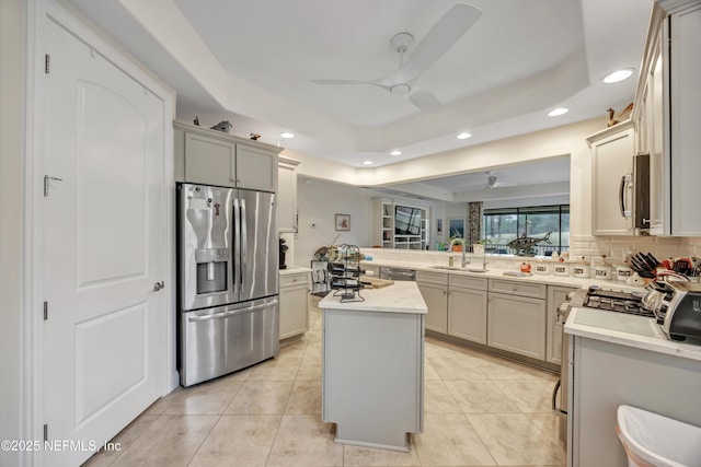 kitchen with sink, a tray ceiling, a center island, and appliances with stainless steel finishes