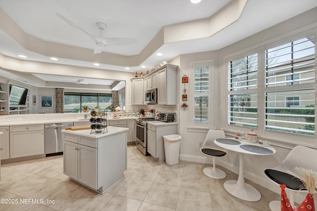 kitchen featuring stainless steel appliances, a raised ceiling, a center island, and light tile patterned flooring