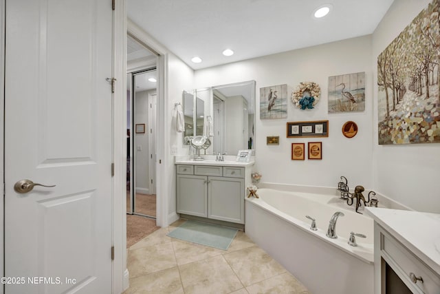 bathroom with a tub to relax in, tile patterned floors, and vanity