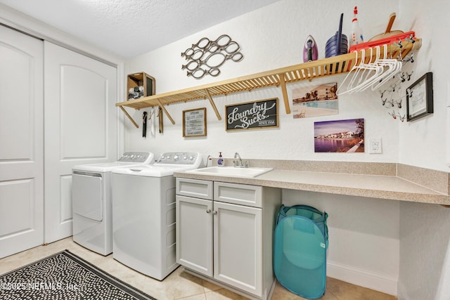 laundry area featuring sink, cabinets, light tile patterned floors, washing machine and clothes dryer, and a textured ceiling