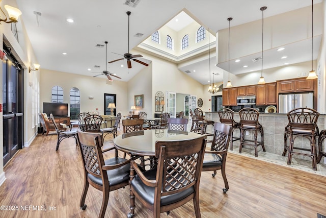 dining room with a towering ceiling and light wood-type flooring