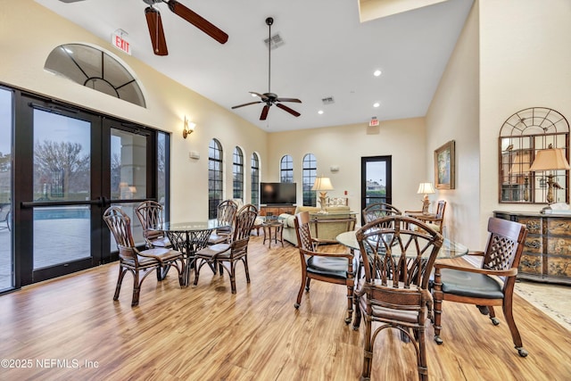 dining area featuring french doors, ceiling fan, light hardwood / wood-style floors, and a high ceiling