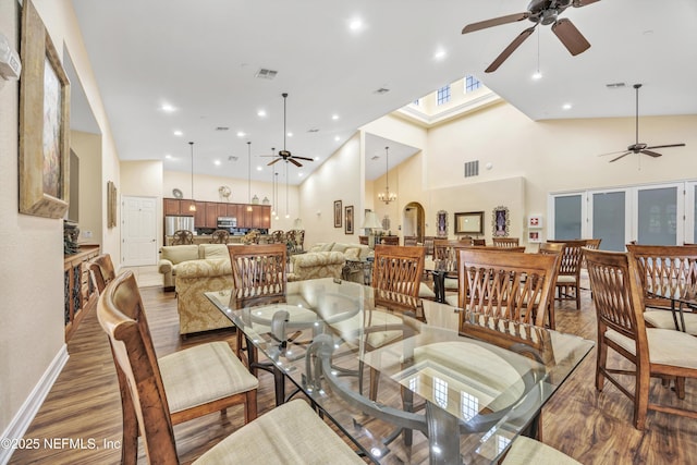 dining area with hardwood / wood-style flooring, a towering ceiling, and ceiling fan