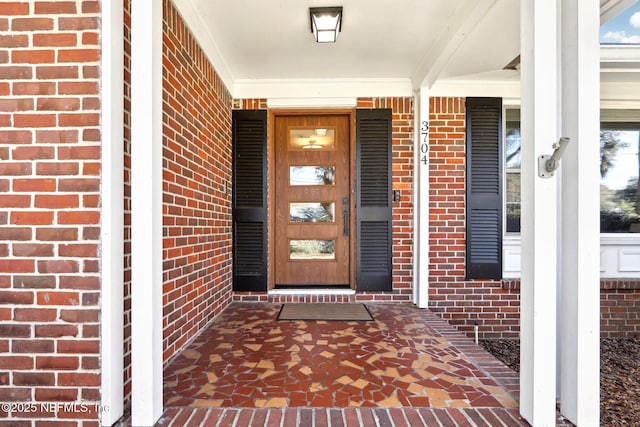 property entrance featuring brick siding and covered porch