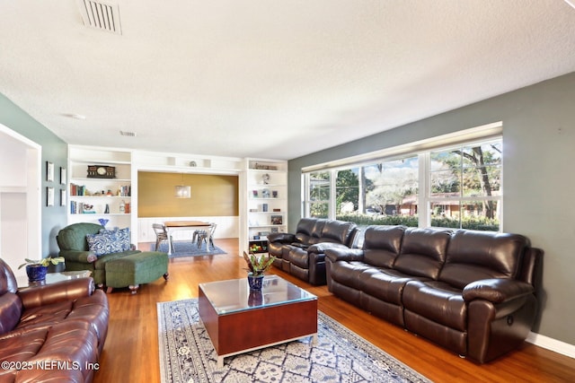 living room with visible vents, a textured ceiling, and wood finished floors