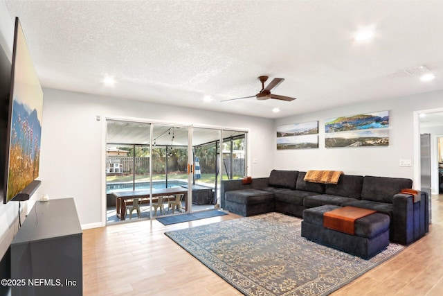 living area featuring a textured ceiling, wood finished floors, a sunroom, and ceiling fan