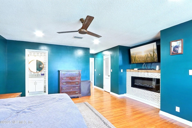 bedroom featuring visible vents, baseboards, wood finished floors, and a tile fireplace