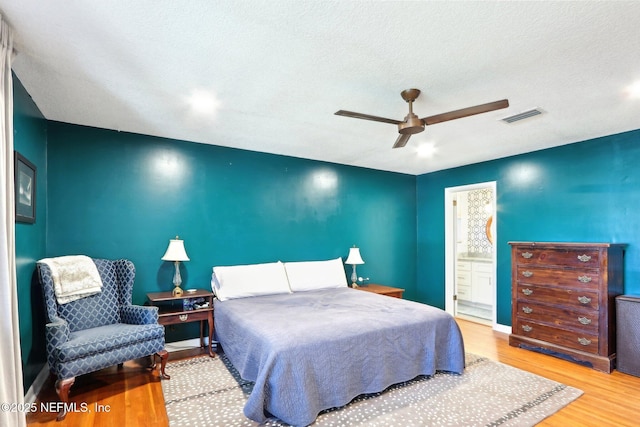 bedroom featuring visible vents, connected bathroom, wood finished floors, a textured ceiling, and a ceiling fan