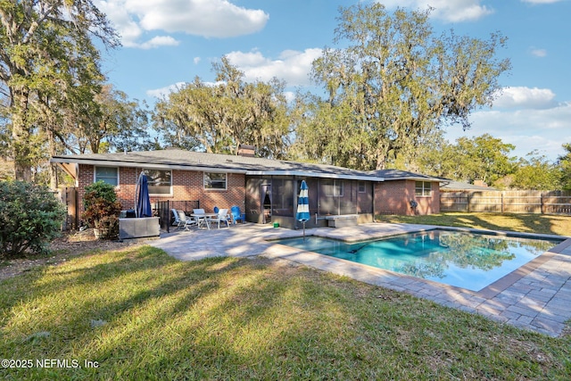 rear view of house featuring a lawn, a fenced backyard, brick siding, and a patio area