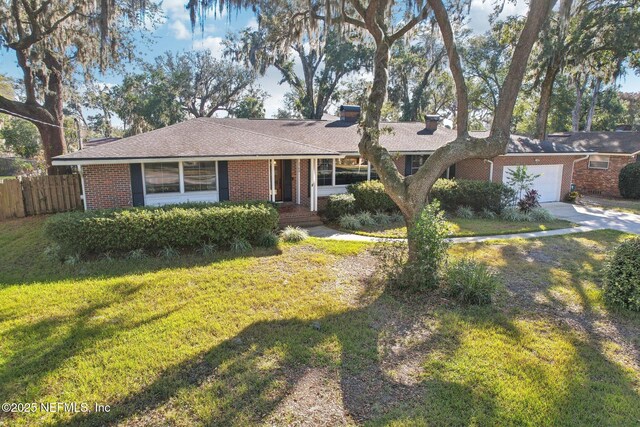 single story home featuring driveway, fence, a front yard, a garage, and brick siding