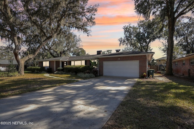 view of front facade featuring a garage, a front yard, brick siding, and driveway