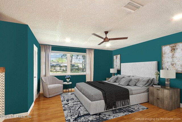 bedroom featuring visible vents, a textured ceiling, wood finished floors, baseboards, and ceiling fan