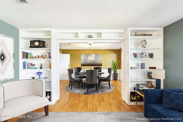 dining room with built in shelves, wood finished floors, and a textured ceiling