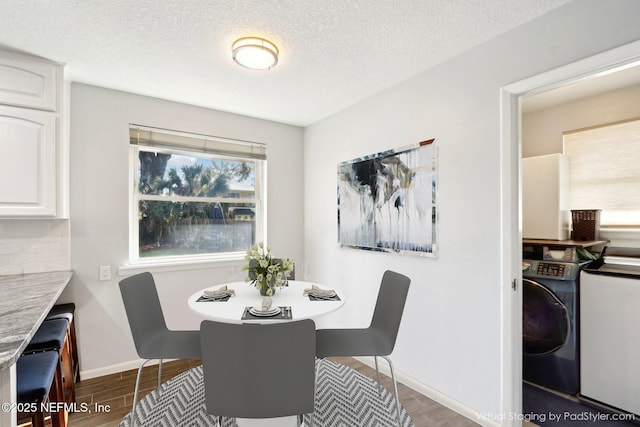 dining room with washer / dryer, a textured ceiling, baseboards, and wood finished floors