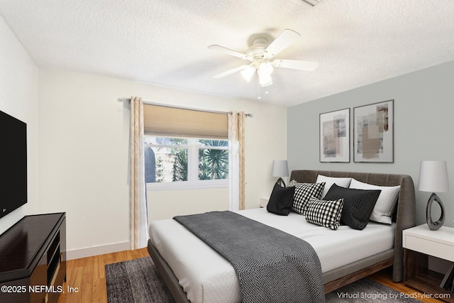 bedroom with baseboards, ceiling fan, a textured ceiling, and light wood-style floors