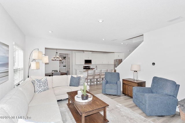 living room featuring light hardwood / wood-style floors, a chandelier, and a textured ceiling