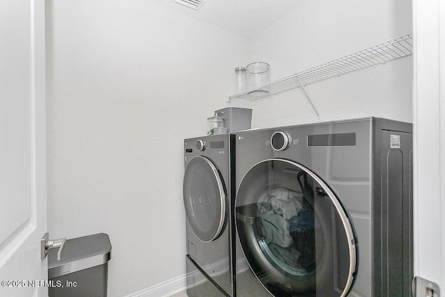 clothes washing area featuring independent washer and dryer, tile patterned floors, and a textured ceiling