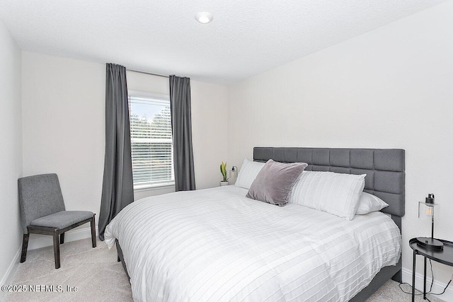 bedroom with light colored carpet and a textured ceiling