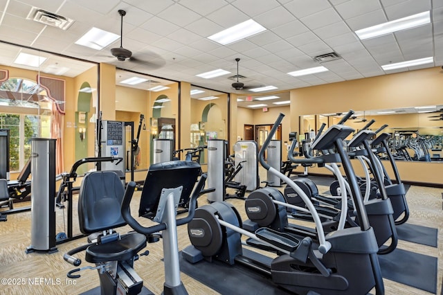 exercise room with light colored carpet, a drop ceiling, and ceiling fan