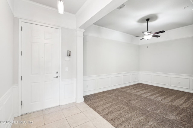 carpeted entryway with beamed ceiling, ceiling fan, ornamental molding, and ornate columns