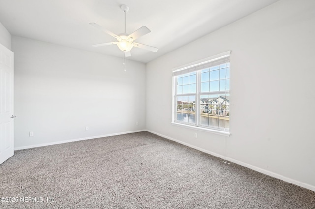 spare room featuring carpet floors, ceiling fan, and a water view