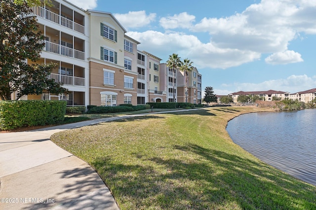 view of property's community with a lawn and a water view