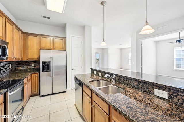 kitchen featuring sink, light tile patterned floors, dark stone countertops, pendant lighting, and stainless steel appliances