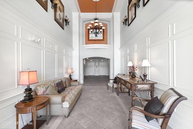 living room featuring light tile patterned flooring, ornamental molding, and a notable chandelier