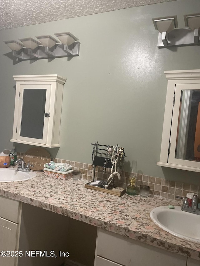 bathroom featuring decorative backsplash, vanity, and a textured ceiling