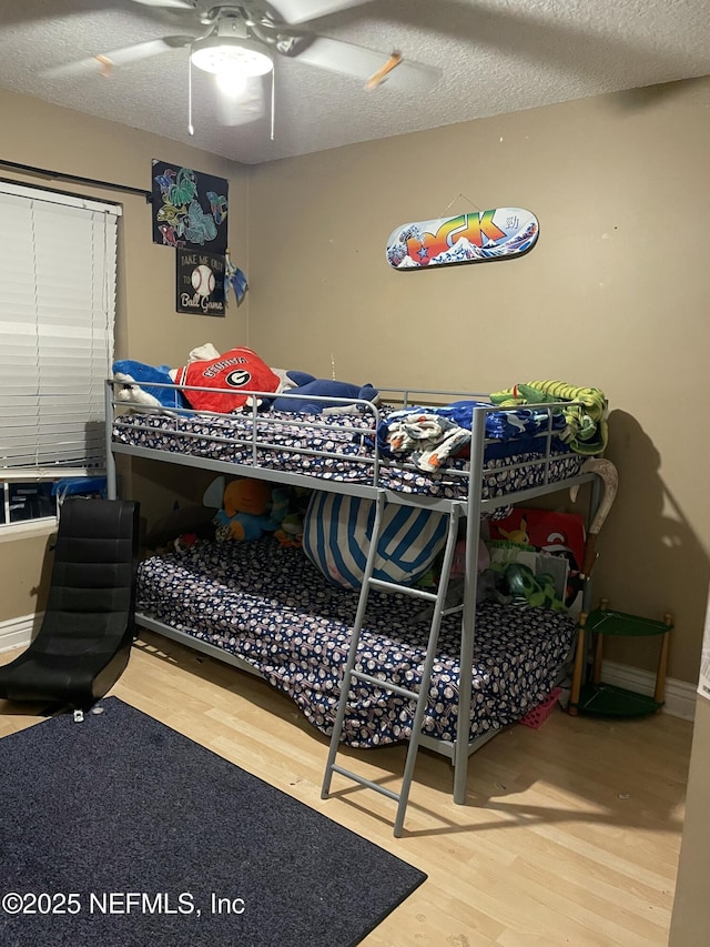 bedroom with hardwood / wood-style floors, a textured ceiling, and ceiling fan