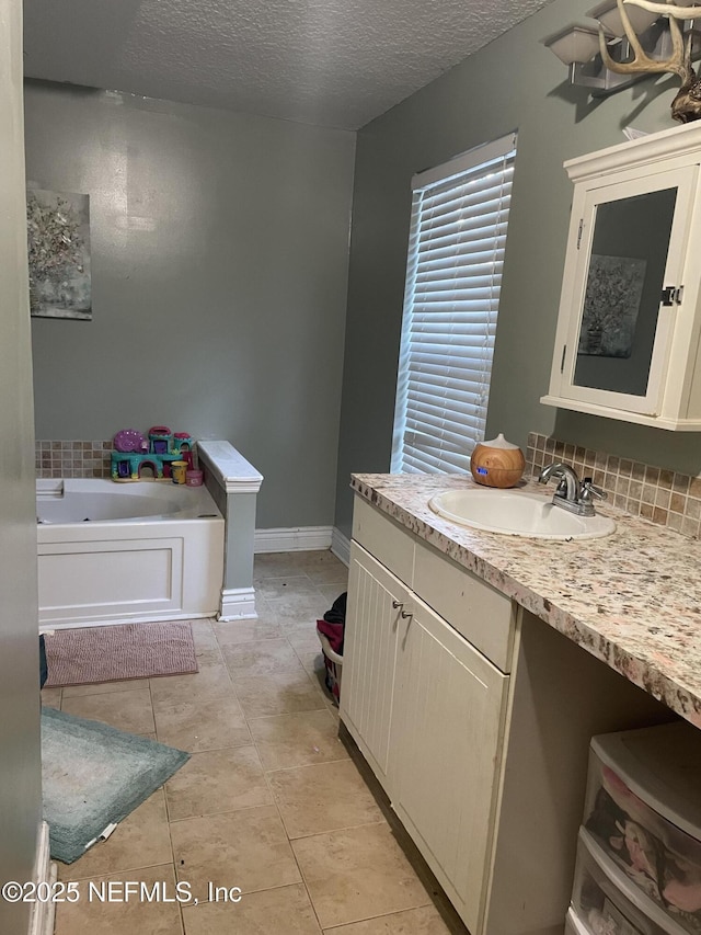 bathroom with a textured ceiling, vanity, a bathing tub, tile patterned flooring, and backsplash