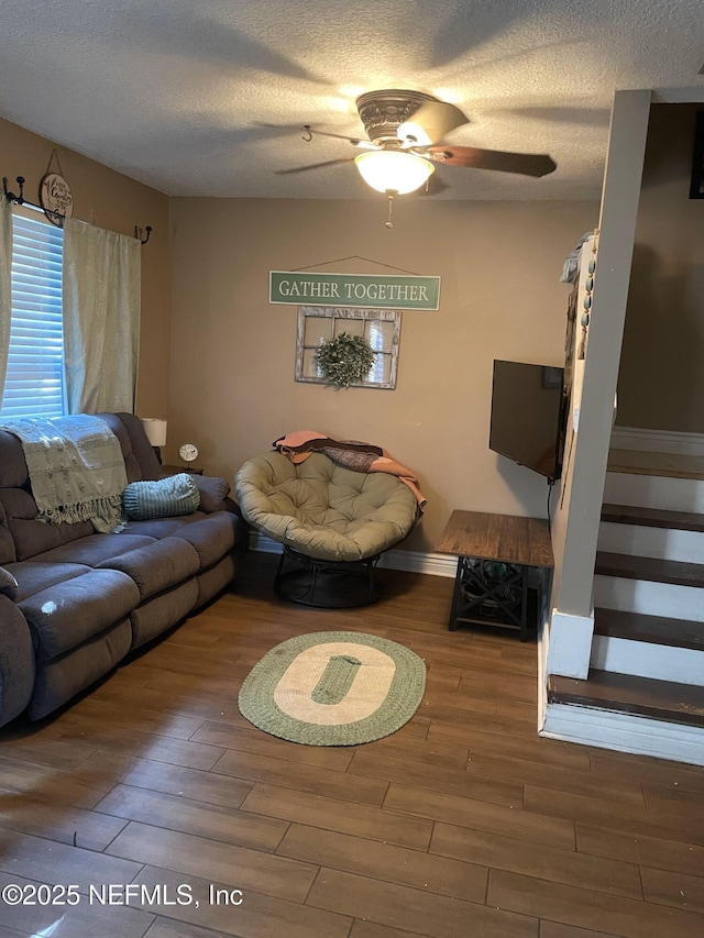 living room featuring ceiling fan, wood-type flooring, and a textured ceiling