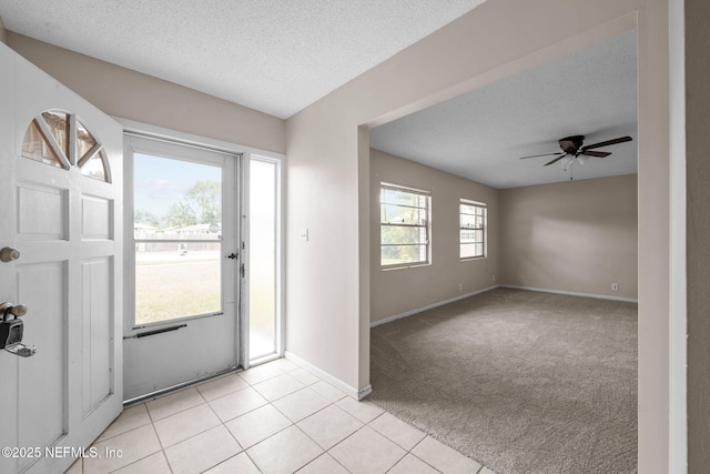 foyer with ceiling fan, light carpet, and a textured ceiling