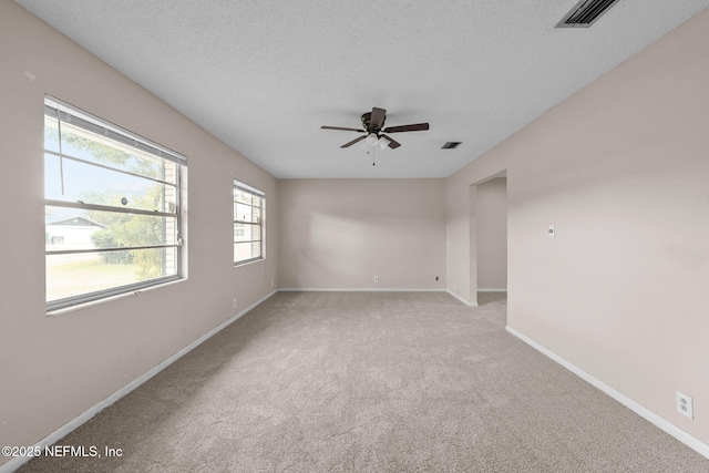 unfurnished room with ceiling fan, light carpet, and a textured ceiling