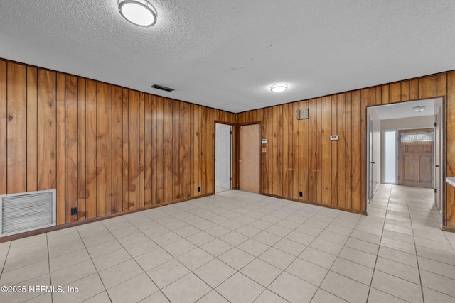 tiled spare room with wooden walls and a textured ceiling