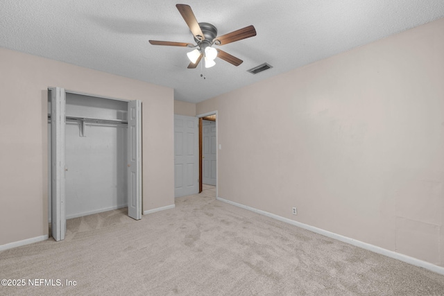 unfurnished bedroom featuring a textured ceiling, light colored carpet, a closet, and ceiling fan