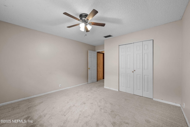 unfurnished bedroom with light carpet, a textured ceiling, a closet, and ceiling fan