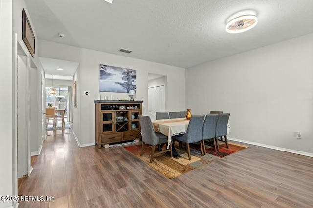 dining room with a textured ceiling and dark hardwood / wood-style flooring